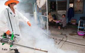 Residents look on as a Public Health ministry dengue prevention worker sprays mosquito repellent in a street outside Bangkok.